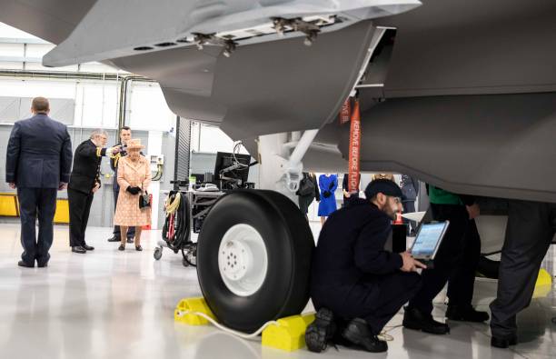 Queen Elizabeth II watches air crew at work on a training model F35B Lightning II fighter at Royal Air Force Marham on February 3 2020 in King's Lynn...