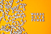 Quote WORDS HAVE POWER made out of wooden letters on bright yellow background.