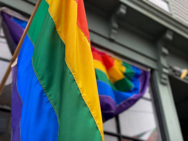 rainbow flag & rainbow flag banner on commercial building front - pride month stock pictures, royalty-free photos & images