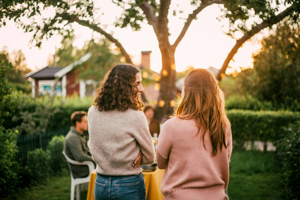 rear view of female friends talking in yard for social gathering - woman talk stock pictures, royalty-free photos & images