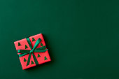 Red gift box on green background. Christmas card. Flat lay. Top view with space for text