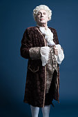 Retro baroque man with white wig standing and looking arrogant.