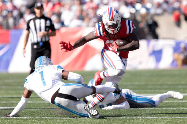 Rhamondre Stevenson of the New England Patriots runs past Jeff Okudah of the Detroit Lions during the first half at Gillette Stadium on October 09,...