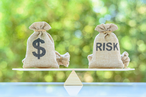 Risk assessment / risk analysis and management concept : Dollar and risk bags on a basic balance scale.