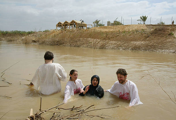 Russian Orthodox pilgrims Gordana Markovich and Igor Kosemko help an elderly worshipper baptize herself in the River Jordan April 22, 2003 at the...