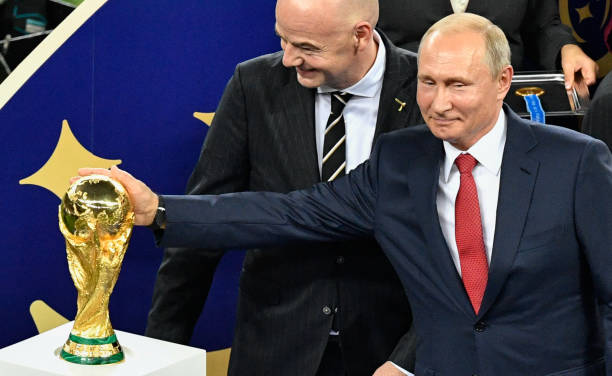 Russian President Vladimir Putin caresses the trophy next to FIFA president Gianni Infantino during the trophy ceremony at the end of the Russia 2018...