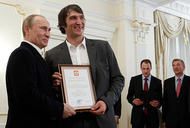 Russian President Vladimir Putin holds a certificate along with Russian national ice hockey team member Alexander Ovechkin thanking Ovechkin for his...