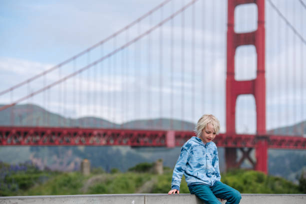 USA, CA, San Francisco, Boy sitting on wall near Golden Gate Bridge