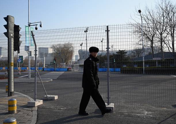 Security guard walks along fencing set up at the Beijing Olympic Park on January 4, 2022 in Beijing, host to the 2022 Winter Olympic Games in one...