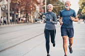 Senior man and senior woman jogging side by side on the street