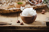 Shea butter in wooden bowl with nuts on old rustic table. Free text space.