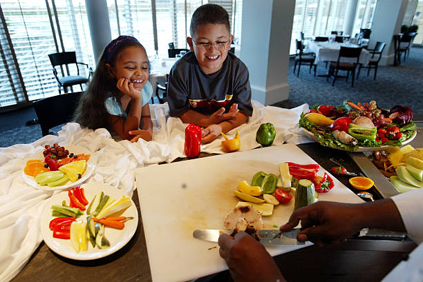 Sheriss Chacon and her brother Shawn Chacon watch as, Eden Roc Renaissance Resort & Spa chef Patrick Barthelemy makes a healthy snack July 2, 2002 in...