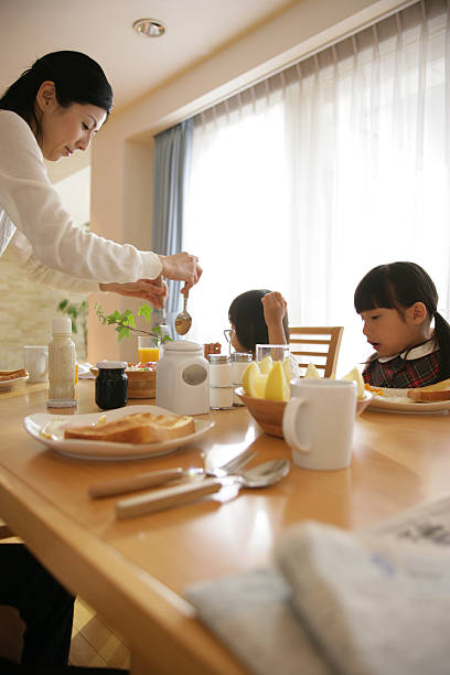 Side profile of a mid adult woman serving her daughters breakfast