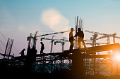 Silhouette of engineer and construction team working at site over blurred background sunset pastel for industry background with Light fair.Create from multiple reference images together.