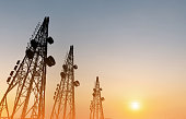 Silhouette, telecommunication towers with TV antennas, satellite dish in sunset