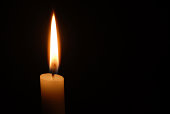 Single candle flame on horizontal black background