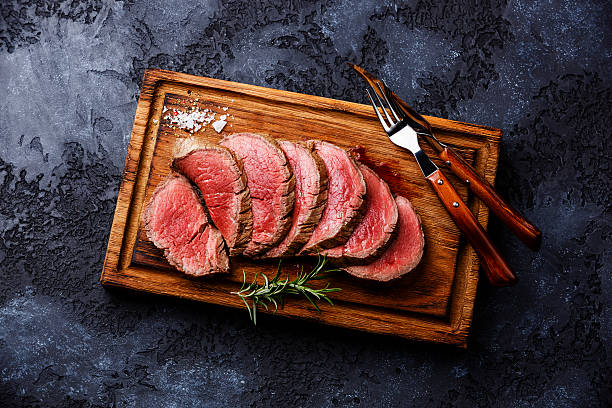 sliced grilled tenderloin steak roastbeef on wooden cutting board on picture