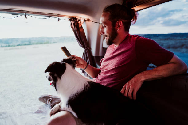 Smiling man using phone by dog in motor home