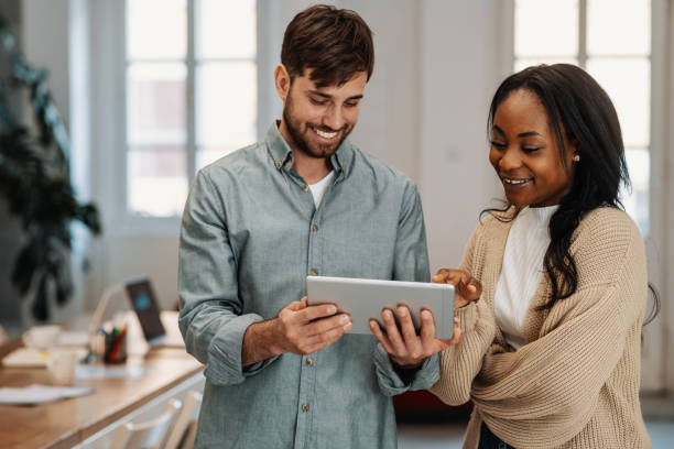 smiling multi ethnic business team in office, using digital tablet - black developer stock pictures, royalty-free photos & images