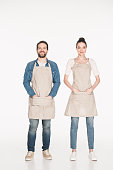 smiling shop assistants in aprons looking at camera isolated on white