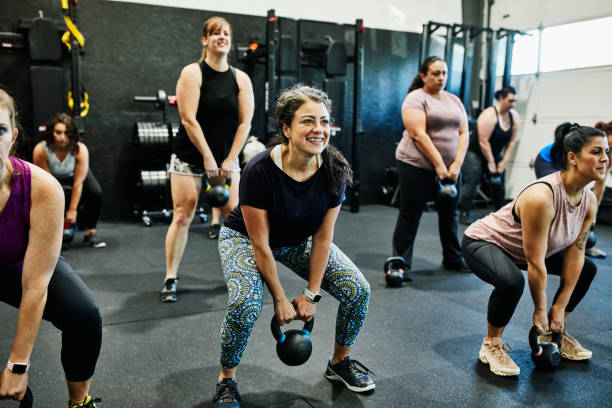 smiling woman doing kettlebell swings while working out during class picture