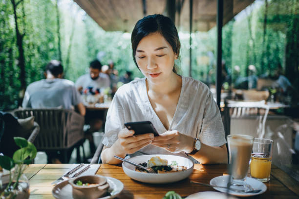 smiling young asian woman using smartphone while having brunch in an picture id1329681998?k=20&m=1329681998&s=612x612&w=0&h=0GahKYw3L8a89wEJsUF1Pm7LCvi GXX8hfONmHm68HQ= - Restaurants: How to Boost Your Customer Attraction.&nbsp;