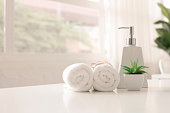 Soap dispenser and spa towel ,Roll up of white towels on white table with copy space,towels studio shot on white table Copy space