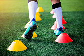 Soccer player Jogging and jump between cone markers on green artificial turf for soccer training.