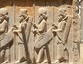 Soldiers of historical empire with weapon in hands. Stone bas-relief in ancient city Persepolis, Iran. Capital of the Achaemenid Empire (550 - 330 BC). UNESCO declared Persepolis a World Heritage Site