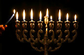 Someone lighting the last candle of a Menorah