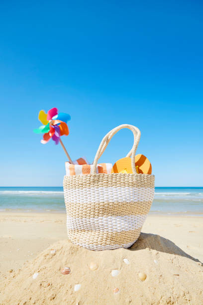 Still life of beach bag and colorful pinwheel at sea against blue sky