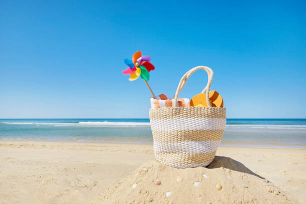 Still life of beach bag and colorful pinwheel at sea against blue sky
