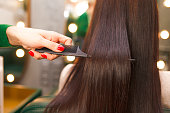 Straight and shiny hair after lamination. Hairdresser demonstrates the result of keratin hair straightening