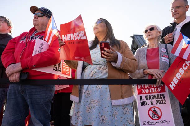 Supporters listen to Georgia Republican Senate nominee Herschel Walker speak during a campaign stop on October 20, 2022 in Macon, Georgia. Walker is...