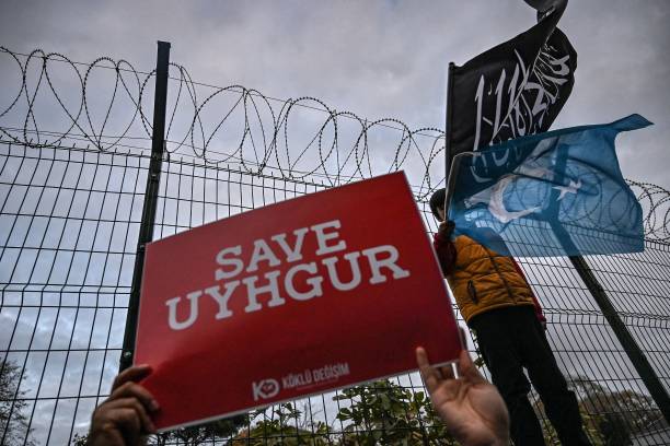 Supporters of China's Muslim Uighur minority holds a placard reading "Save Uighur" as a boy waves the flag of East Turkestan and an Islamic black...