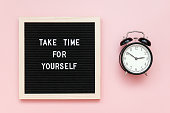 Take time for yourself. Motivational quote on letterboard and black alarm clock on pink background. Top view Flat lay Copy space Concept inspirational quote of the day