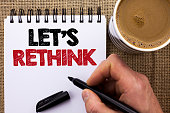 Text sign showing Let Us Rethink. Conceptual photo Give people time to think things again Remodel Redesign written by Man Holding Marker on Notebook Book on the jute background Coffee Cup.