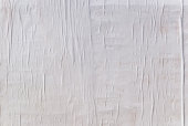 Texture of wet white folded paper on an outdoor poster wall, crumpled paper background