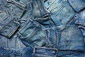 Textured background with variety of mens and womens blue jeans.