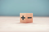 The concept of opposites, wood blog with plus and minus on blue background.