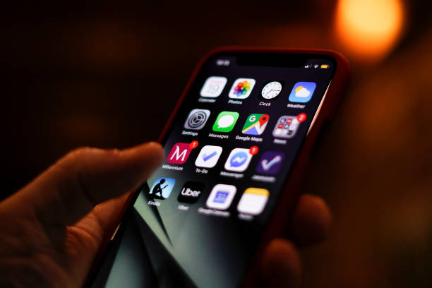 The home screen of an Apple iPhone is seen displayed on a mobile device in front of a screen with data in this photo illustration in Warsaw, Poland...