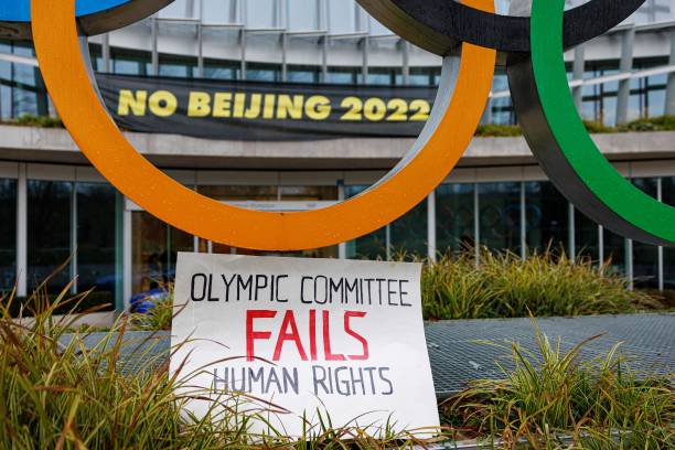 This photograph taken on December 11, 2021 shows a placard at the entrance of the International Olympic Committee headquarters during a demonstration...