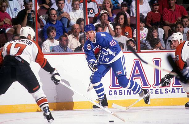 tim-hunter-of-the-quebec-nordiques-passes-the-puck-against-rod-of-picture-id128778405