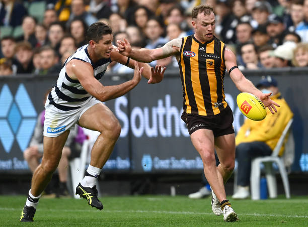 Tom Mitchell of the Hawks kicks whilst being tackled by Tom Hawkins of the Cats during the round five AFL match between the Hawthorn Hawks and the...