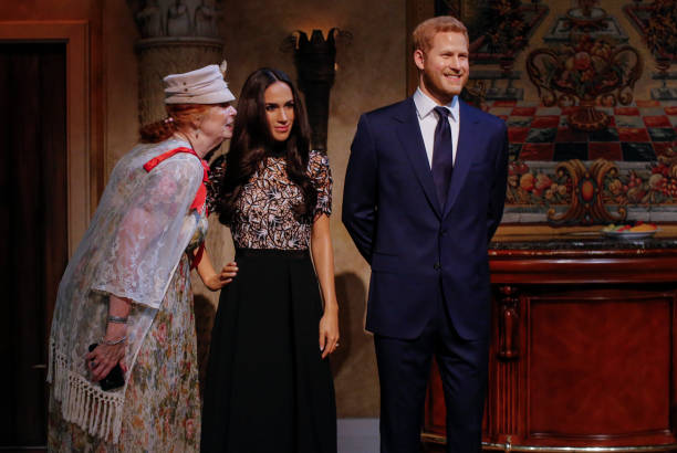 Tourists pose next to wax sculptures of Meghan Markle and Prince Harry as they attend a royal wedding watch party at the Madame Tussauds wax museum...