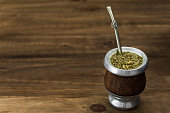 Traditional Argentinian yerba mate tea in a calabash gourd with bombilla stick against wooden background
