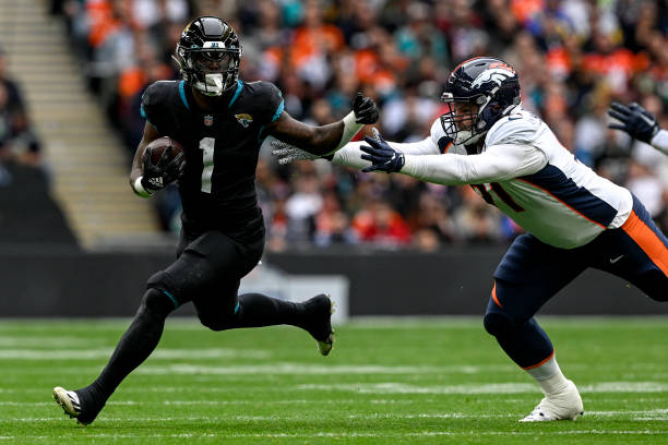 Travis Etienne Jr. Of the Jacksonville Jaguars evades Matt Henningsen of the Denver Broncos during the first quarter at Wembley Stadium in London on...