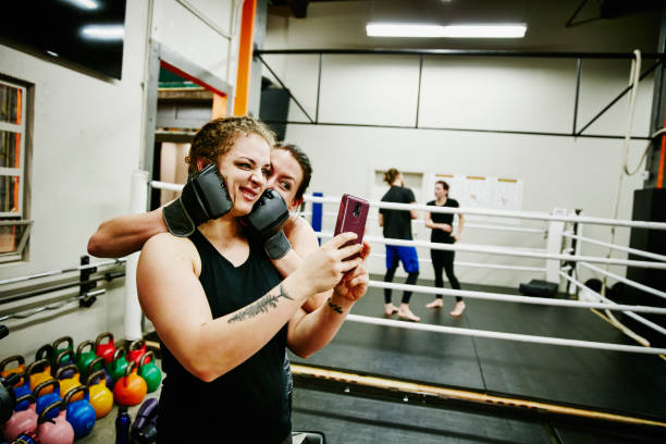 Two female fighters taking self portrait with smartphone after training session in gym