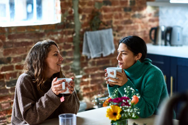 two women enjoying hot drink having conversation - woman listening stock pictures, royalty-free photos & images