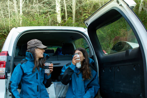 two women park rangers on their coffee break leaning on their 4x4 car